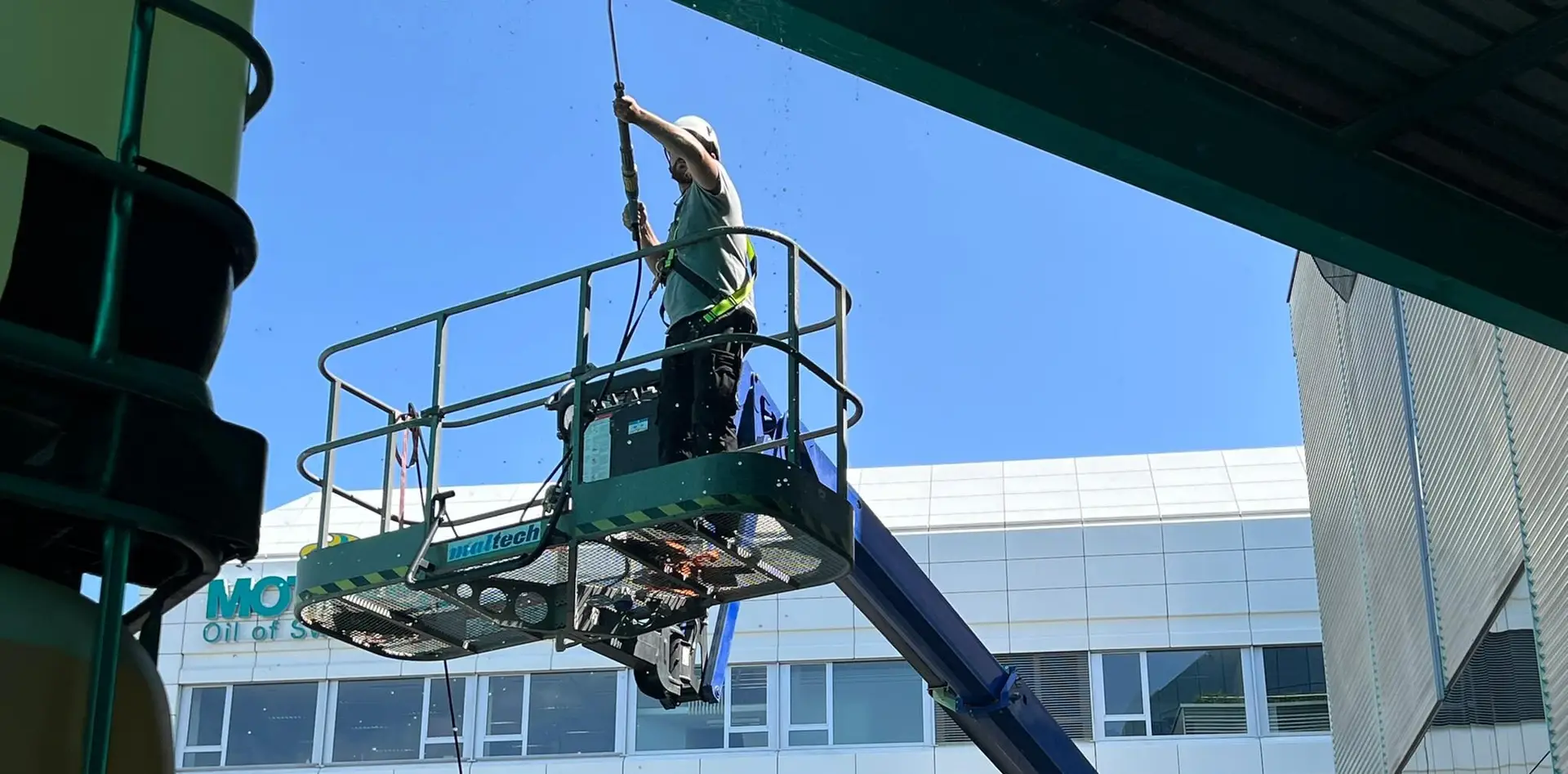 Arbeiter bei Fassadenreinigung mit Hebebühne an moderner Gebäudefassade.